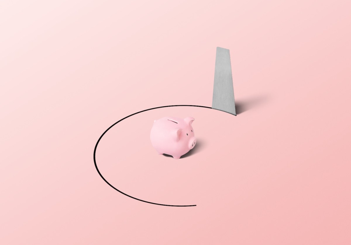 Ein Sparschwein in einer gefangenen Position mit einer Handsäge.