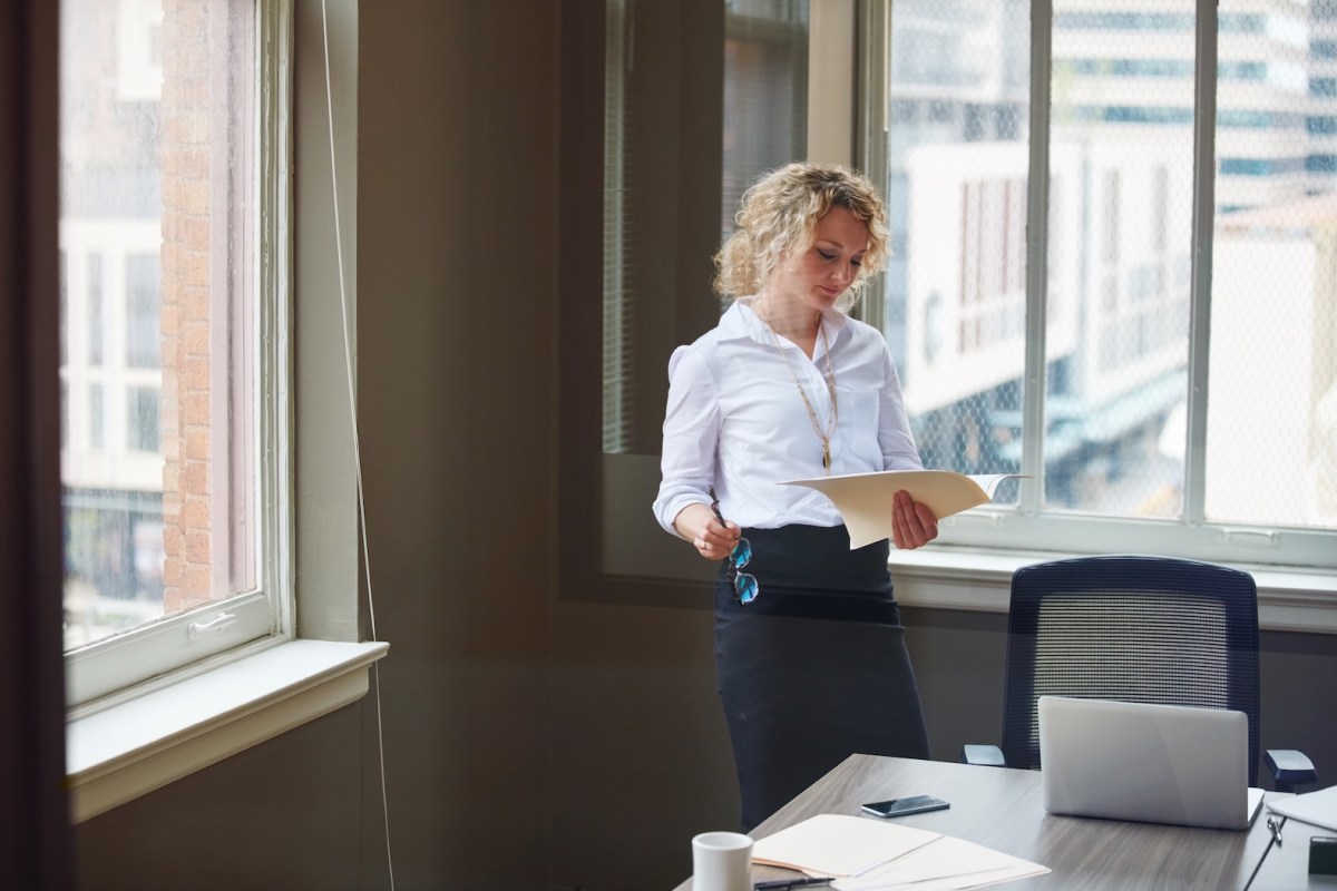Aufnahme einer Geschäftsfrau, die in einem Büro einen Bericht liest.