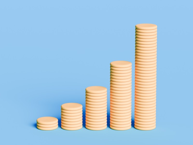 Fünf aufsteigende Stapeln gelber Münzen vor blauem Hintergrund.