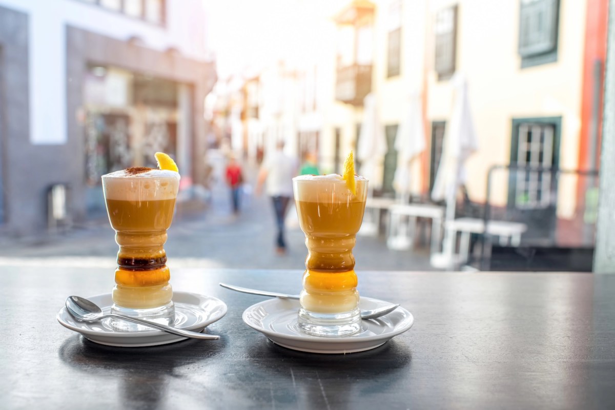 Traditioneller kanarischer Kaffee Barraquito auf dem Tisch mit Stadt im Hintergrund.