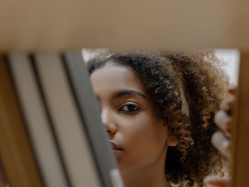 Frau schaut durch Bücherregal.