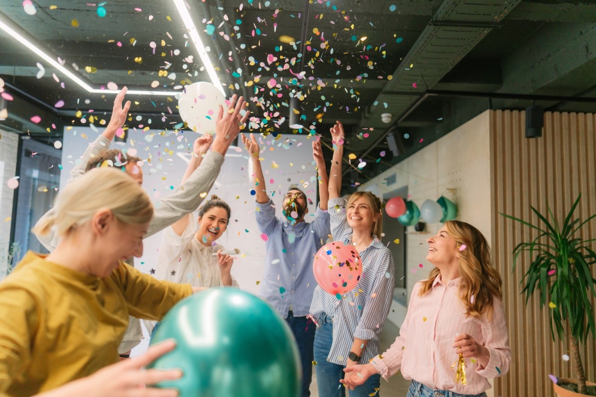 Foto einer Gruppe von Kollegen, die einen freudigen Anlass haben und gemeinsam an ihrem Arbeitsplatz feiern.