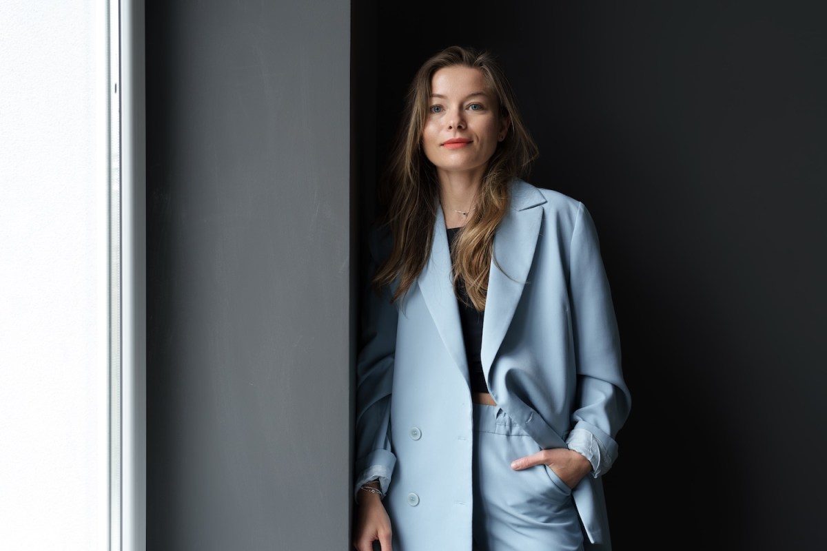 Moderne junge Geschäftsfrau trägt lässige Kleidung posiert drinnen.