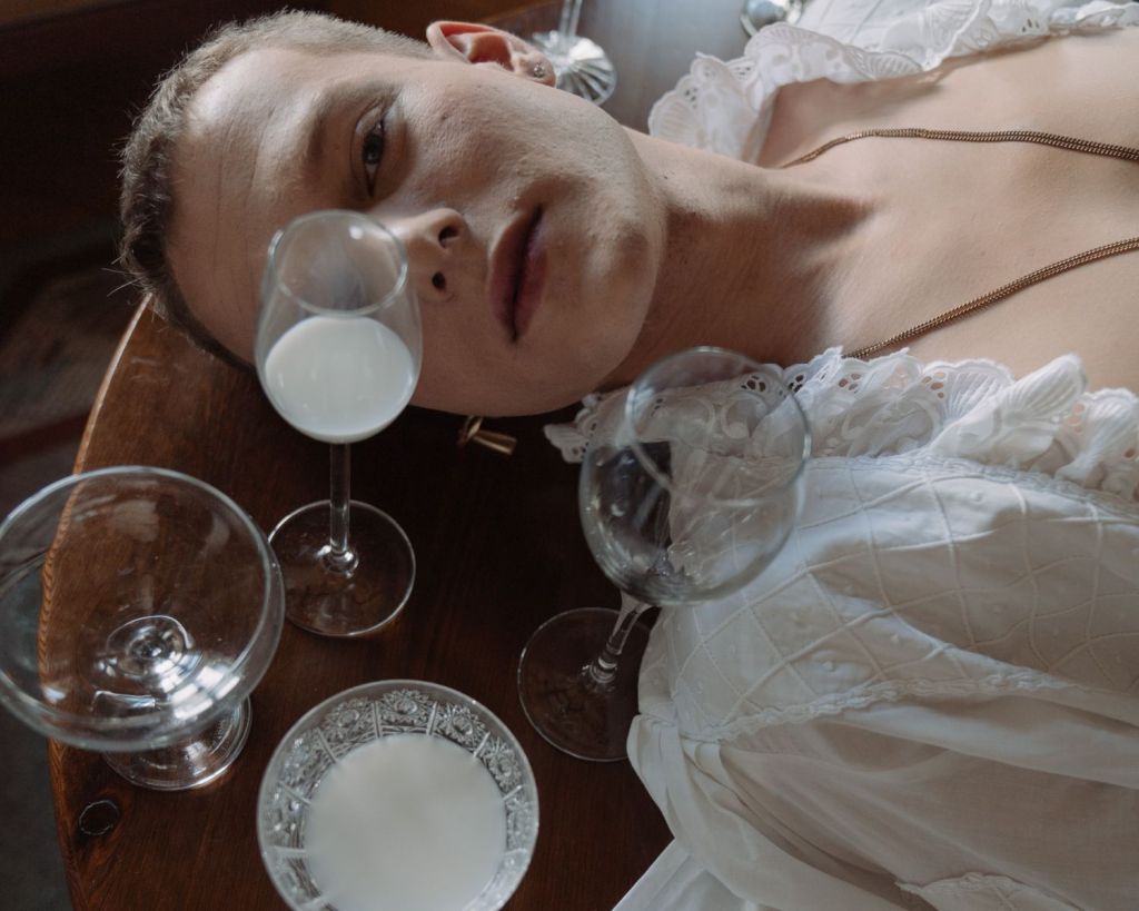 Mann liegt auf einem Tisch, umgeben von Kristallgläsern.