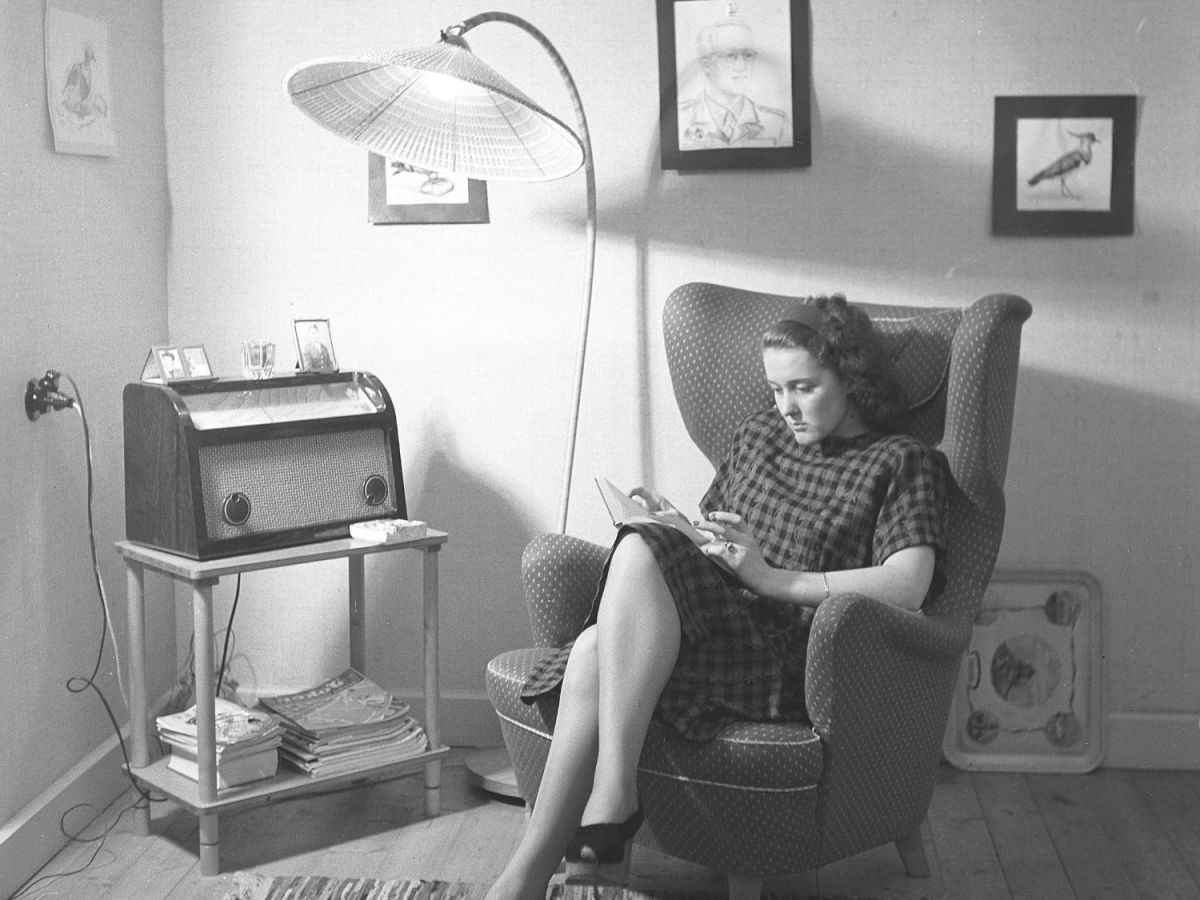 Frau sitzt auf einem Sessel und liest; in Schwarz-Weiß.