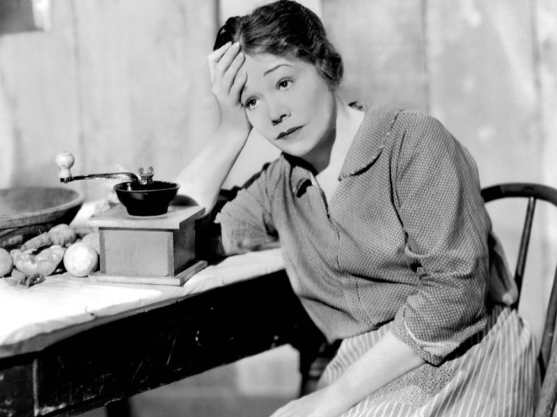 Oma sitzt am Tisch mit einer Kaffeemühle darauf