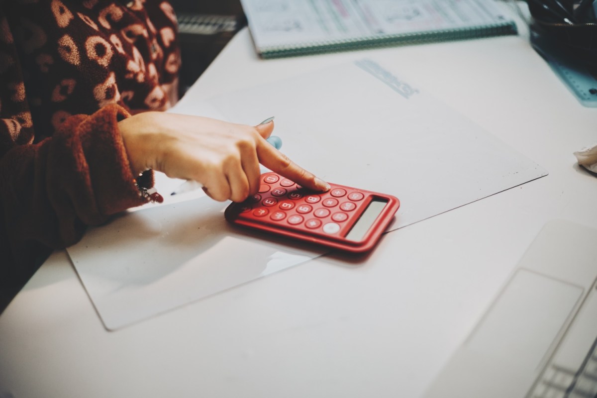Eine Frau tippt auf einem Taschenrechner.