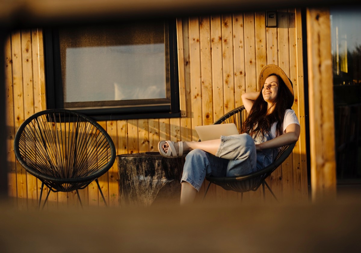 Frau benutzt Laptop während der Arbeit auf ihrer Terrasse.