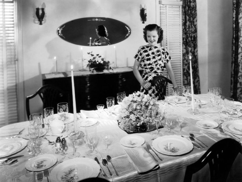 Frau deckt einen Tisch in Schwarz-Weiß.