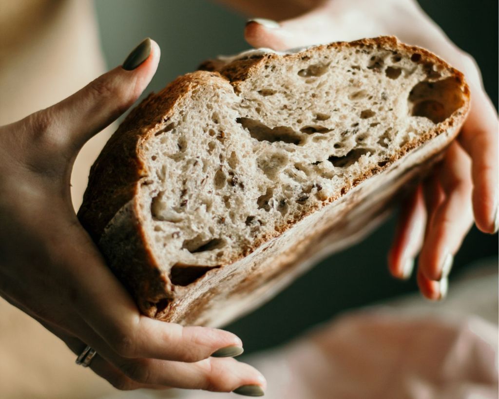 Frauenhände halten aufgeschnittenes Brot.