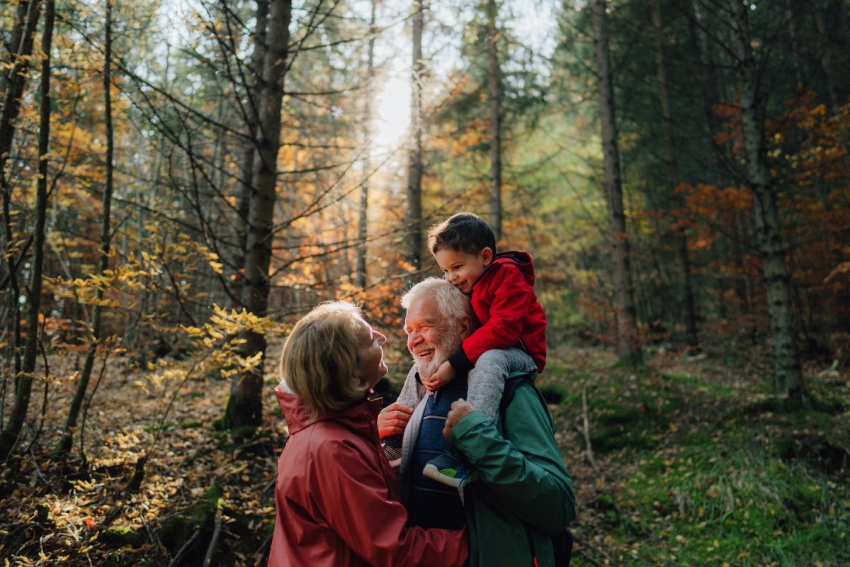 Foto von Großeltern und ihrem Enkel bei einem Spaziergang durch den Wald.