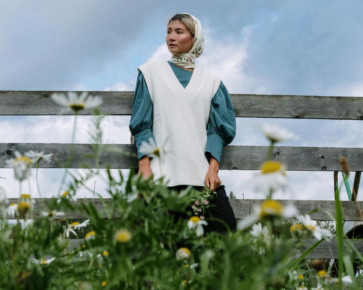 Frau steht vor einem Zaun