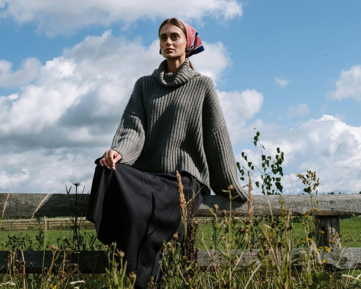 Frau sitzt auf einem Weidezaun