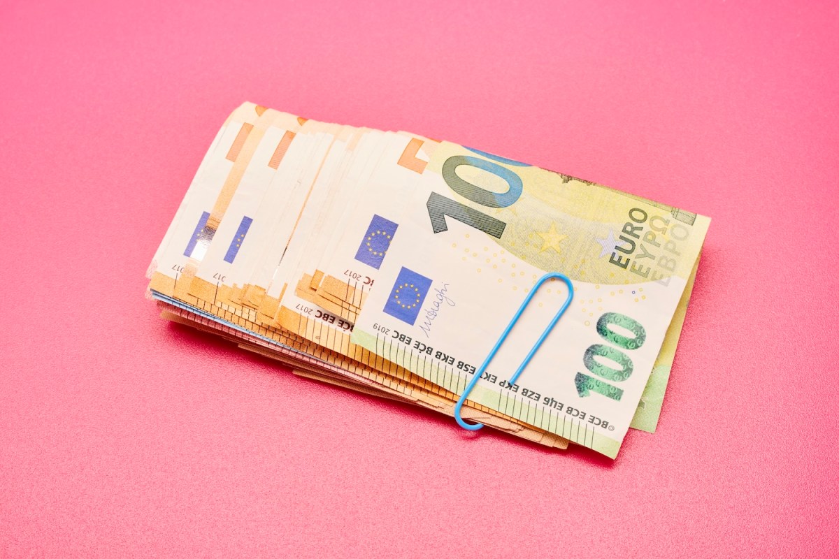 Ein Bündel Euro-Banknoten auf rosa Hintergrund.