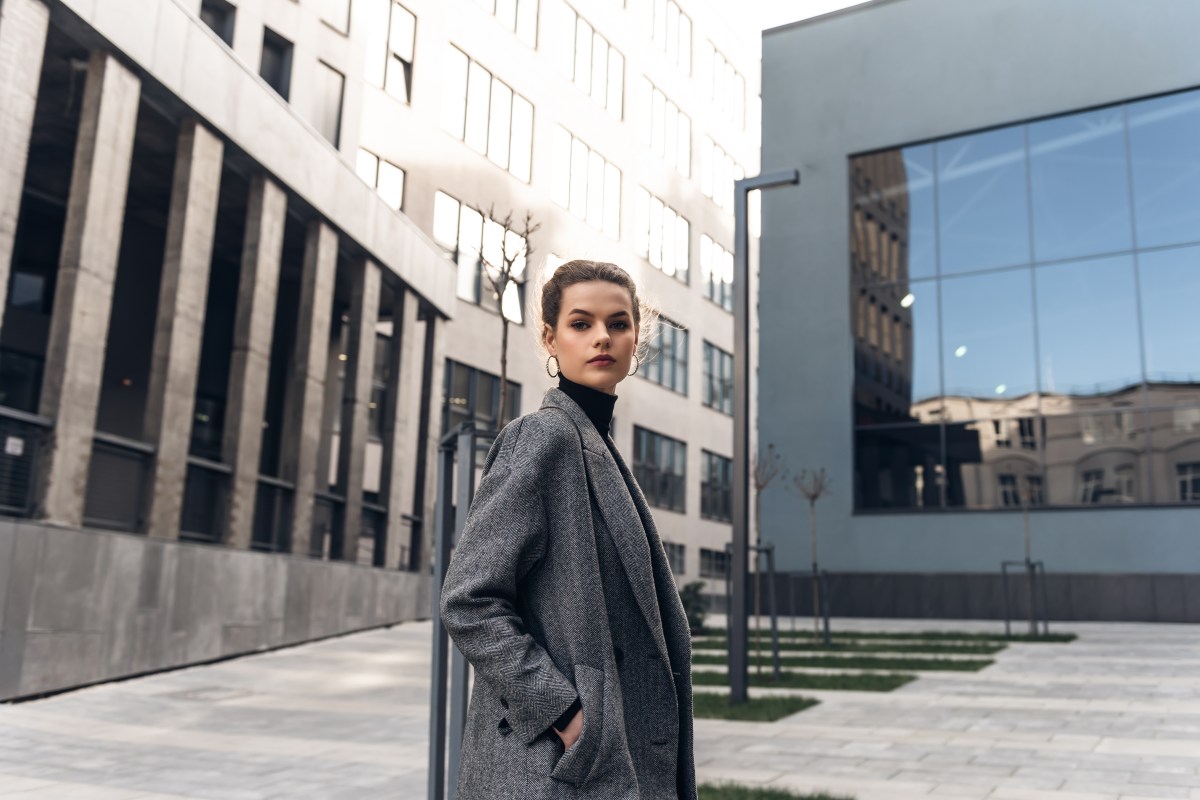 Eine selbstbewusste Frau steh vor einem Bürogebäude.