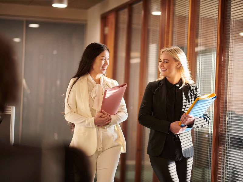 Zwei junge Frauen laufen durch ein Büro.