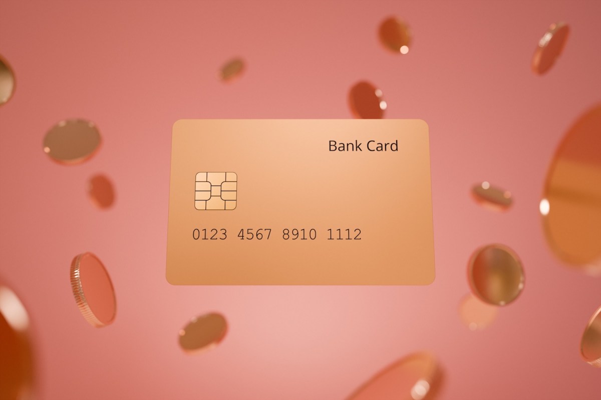 Eine Bankkarte in Goldtönen schwebt zwischen mehreren Münzen vor einem minimalistischen rosa Hintergrund.