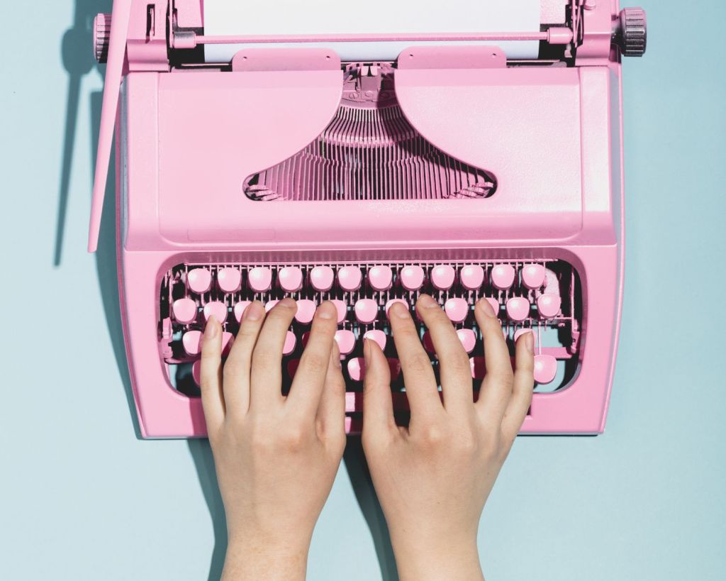 Finger tippen auf einer pinken Schreibmaschine