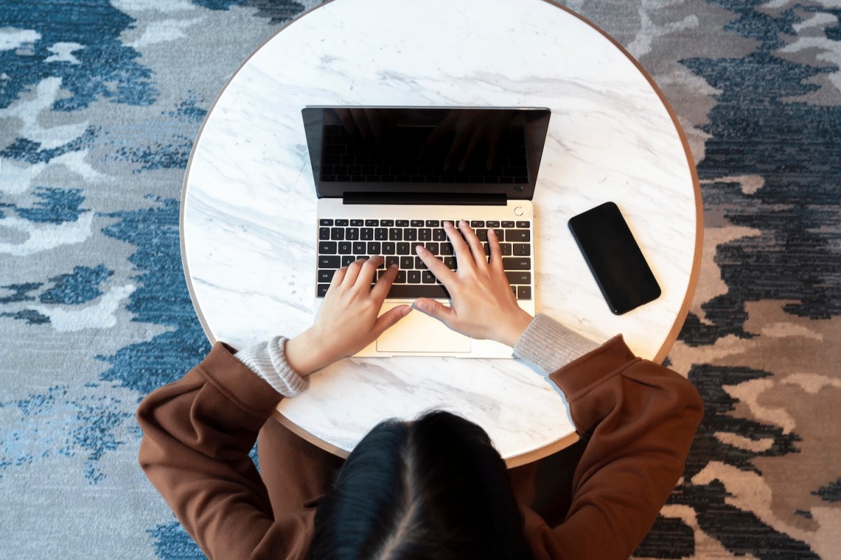 Eine Frau mit schwarzem Haar tippt auf dem Laptop.