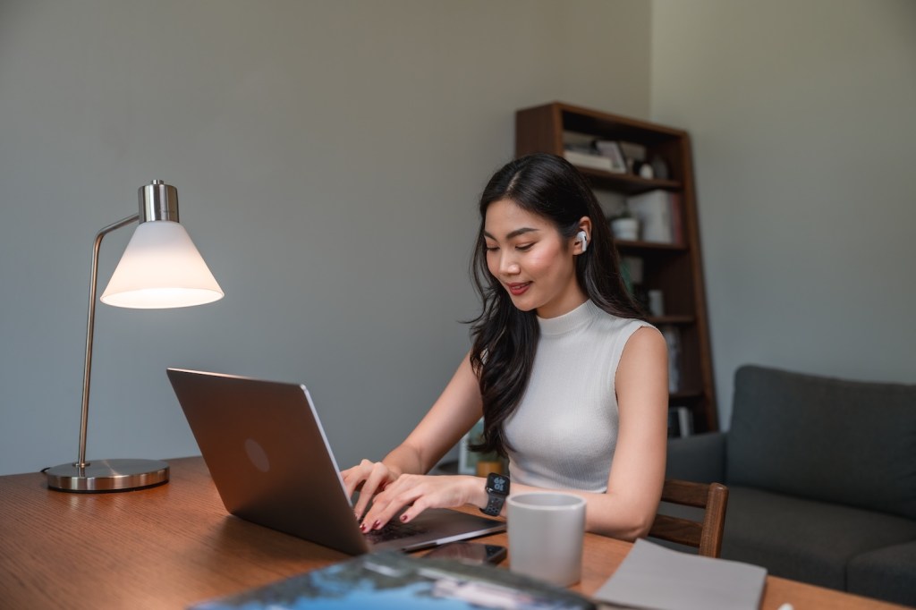 Nahaufnahme einer Frau, die ihren Lebenslauf für die Online-Stellensuche an ihrem Laptop aktualisiert.