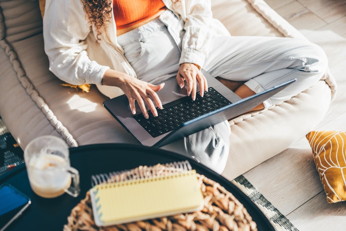 Eine junge Frau schreibt eine Bewerbung in ihrem Wohnzimmer.