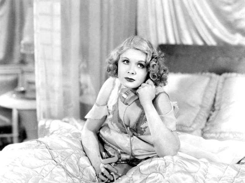 Frau mit einem Telefon im Bett in Schwarz-Weiß