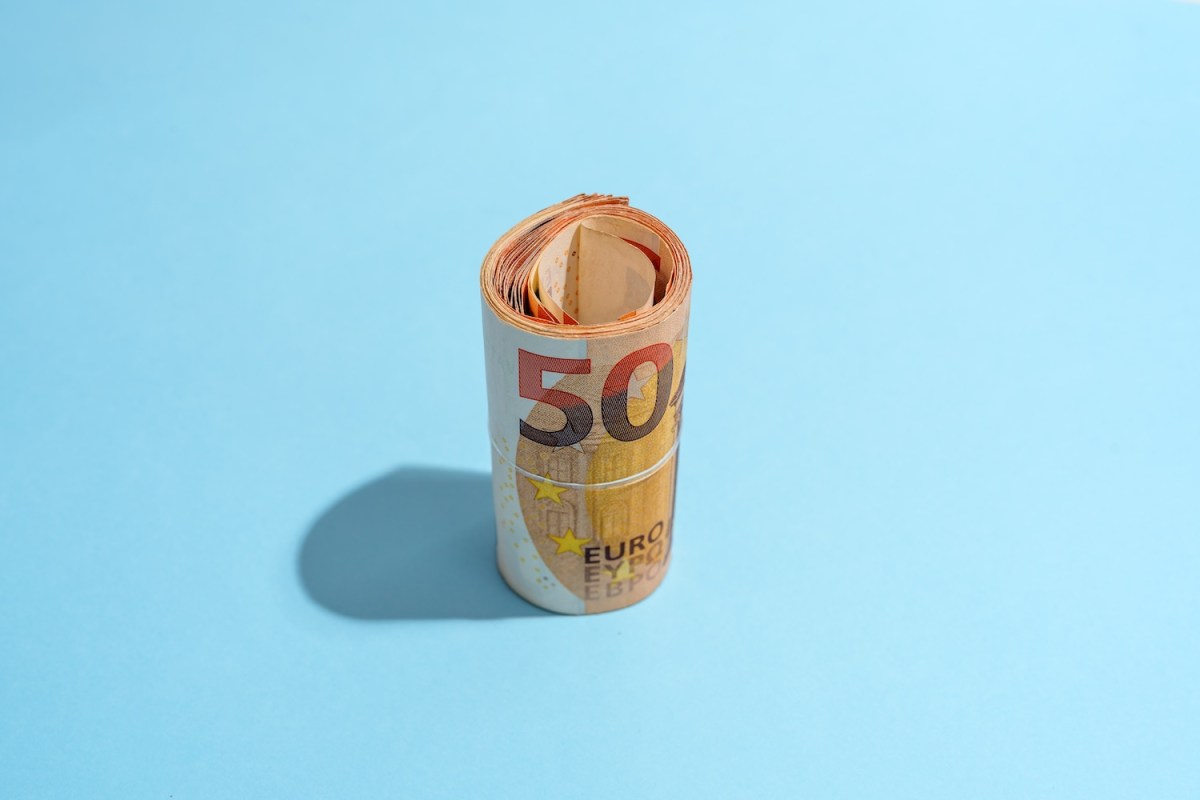 Eine Geldrolle mit 50-Euro-Scheinen auf blauem Hintergrund.