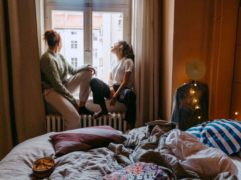 Zwei Frauen sitzen auf einer Heizung am Fenster