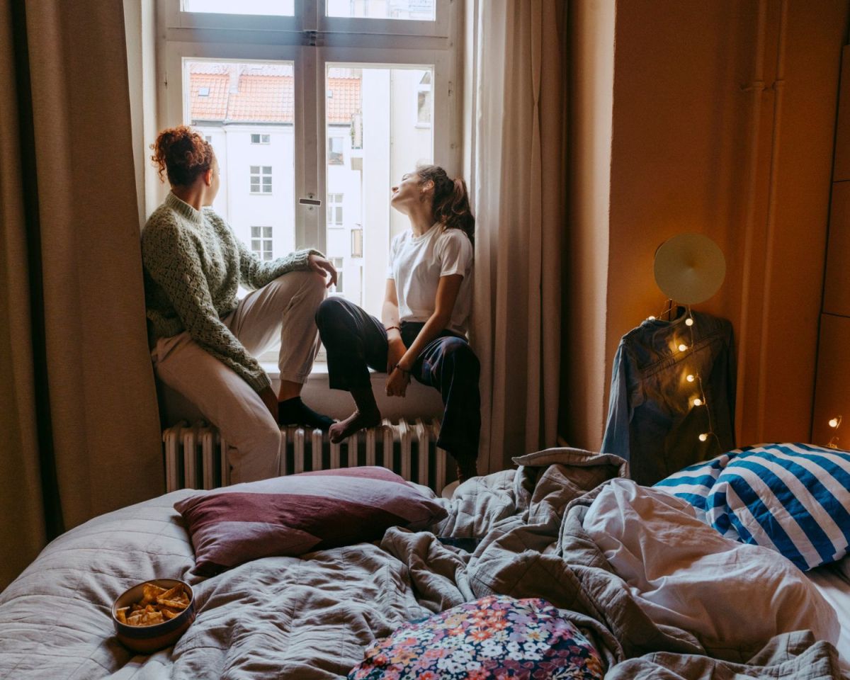 Zwei Frauen sitzen auf einer Heizung am Fenster