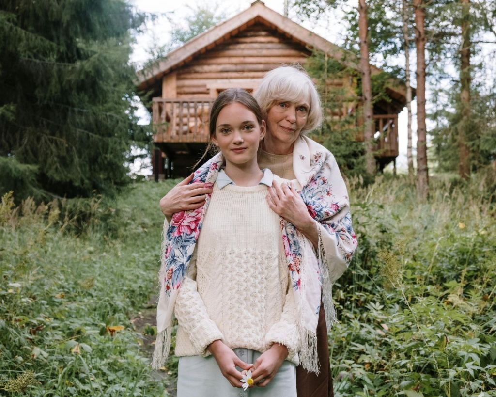 Oma und Enkelkind vor einer Hütte im Wald