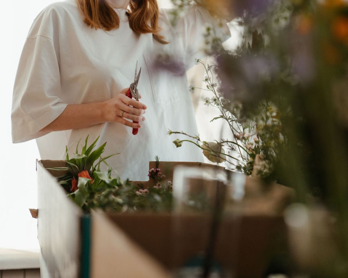 Frau mit Schere in der Hand, um Rückschnitt für Pflanzen vorzunehmen.