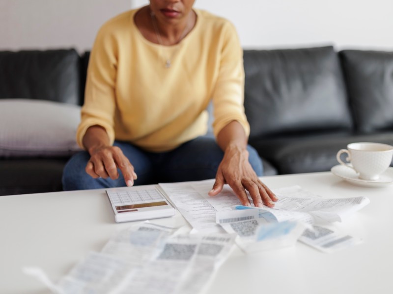Frau, die im Wohnzimmer sitzt und ihre Steuerunterlagen prüft.
