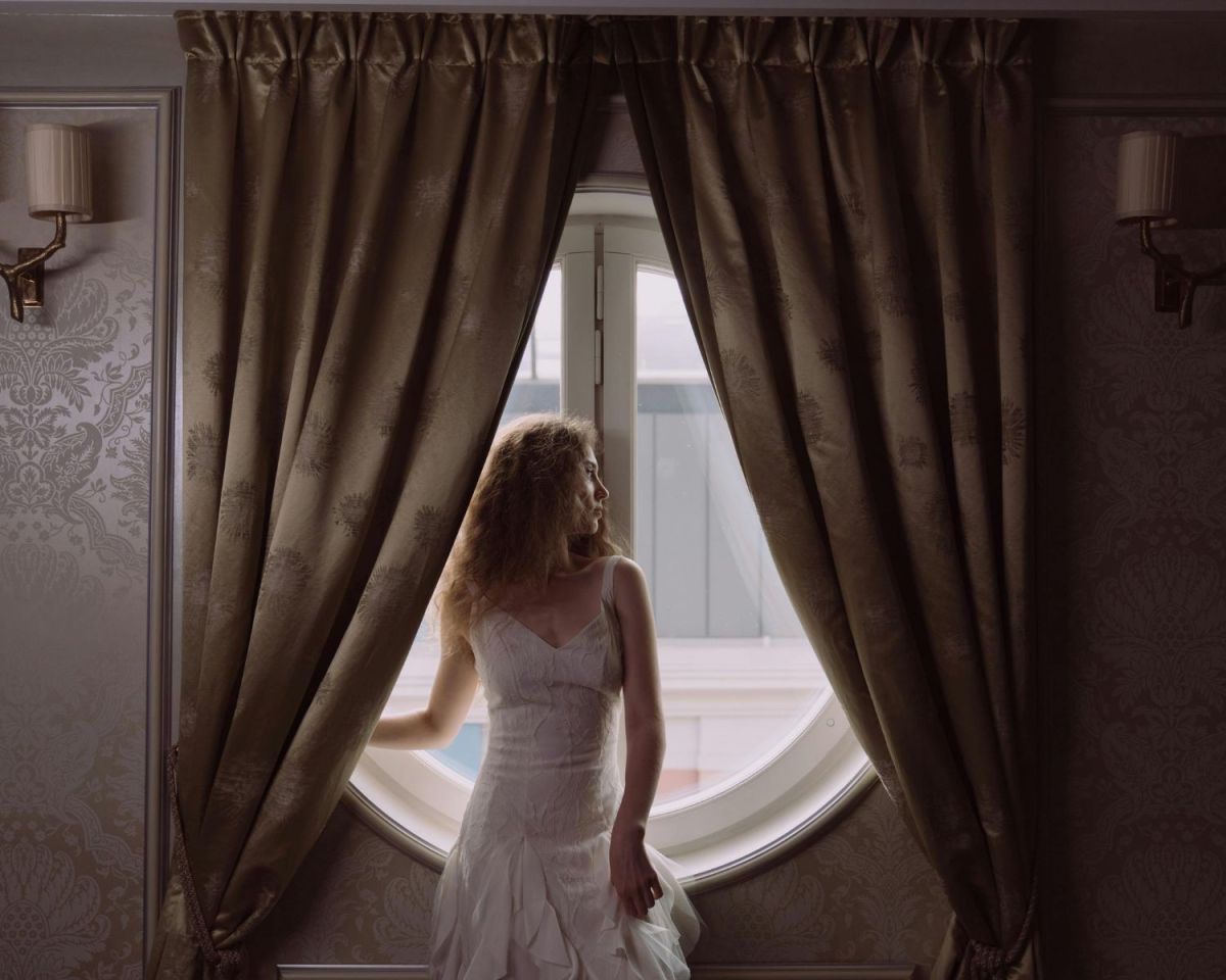 Frau steht vor einem Vorhang