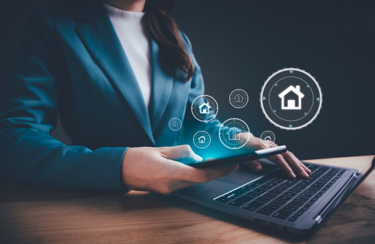 Eine Frau sitzt am Laptop. Darum erscheinen Finanzsymbole.