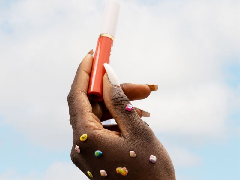 Frau hält einen Lipgloss in die Luft Balea-Dupe