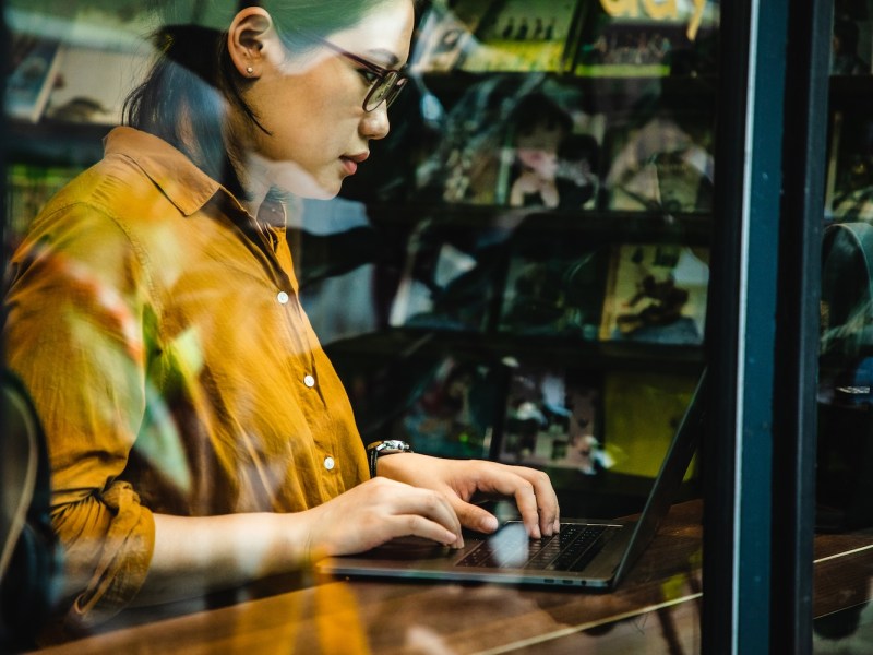 Eine Frau sitzt am Laptop und schreibt.