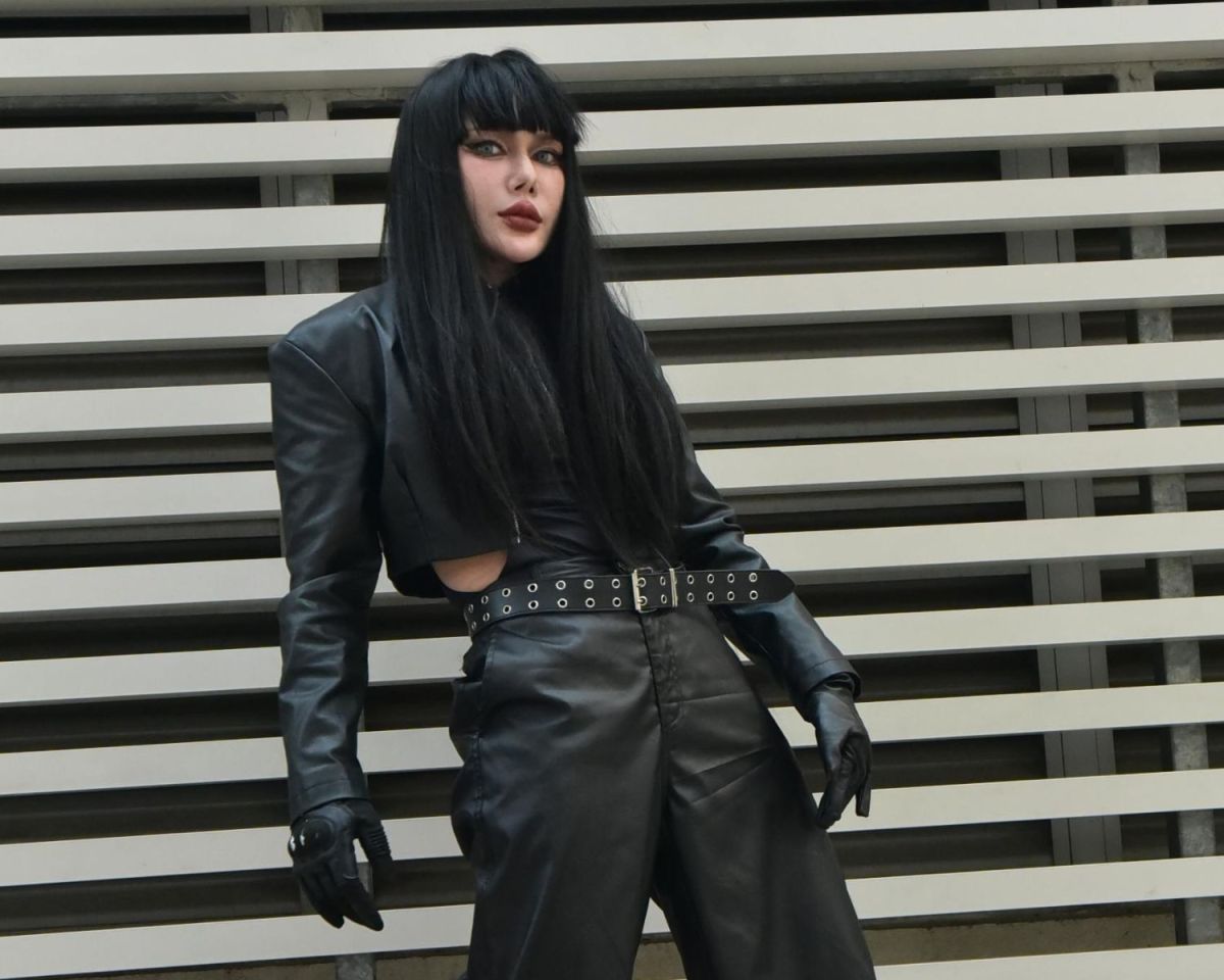 Junge Frau lehnt an einer Wand mit Lederjacke