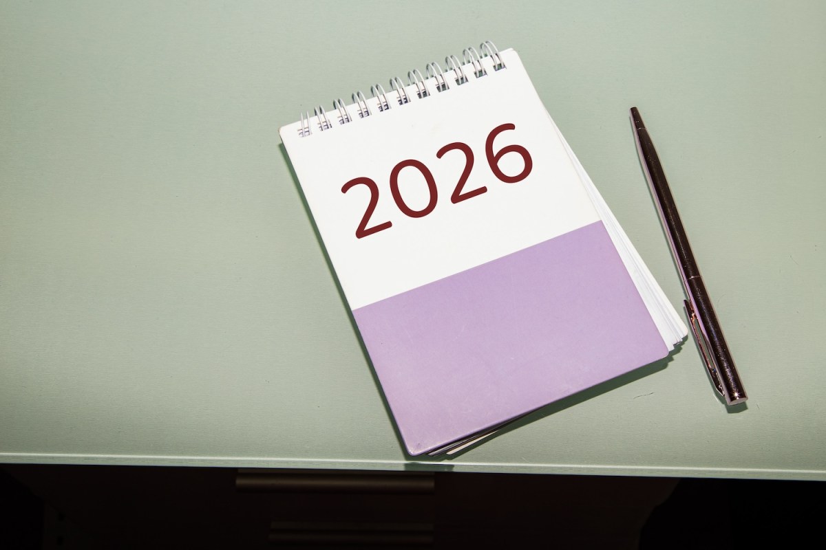 Ein minimalistisches Foto eines Notizbuchs mit der Aufschrift „2026“ auf dem Einband, das auf einem pastellgrünen Schreibtisch liegt.