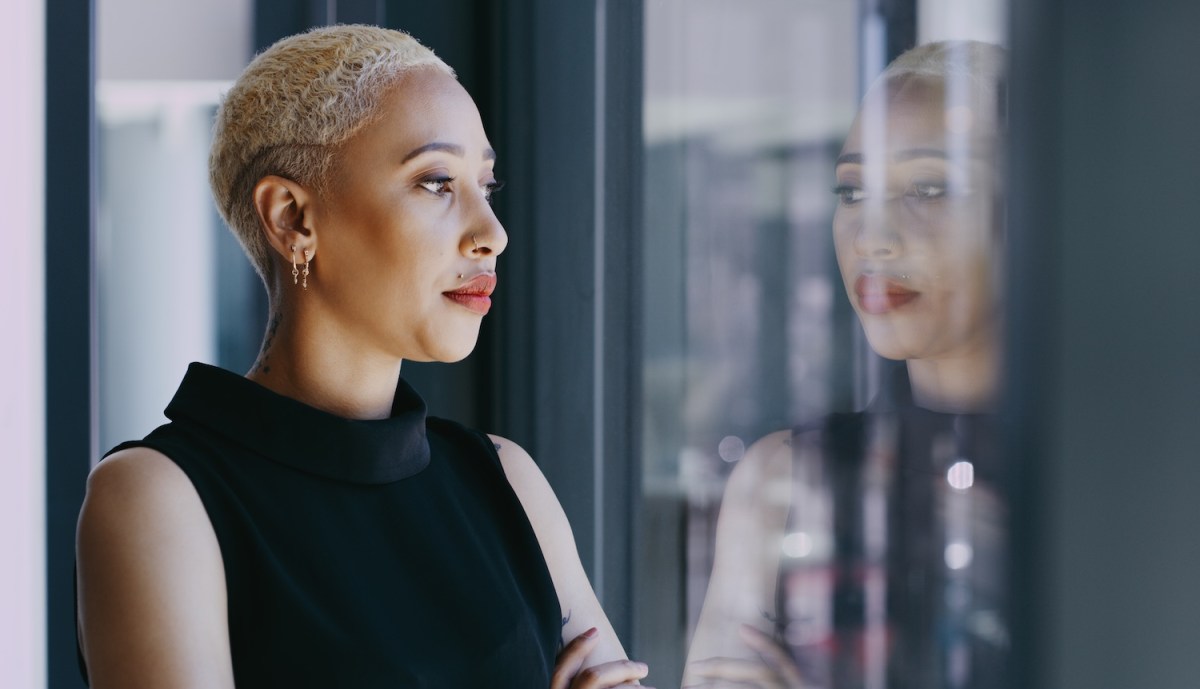 Eine Frau mit kurzen blonden Haaren schaut aus dem Fenster.