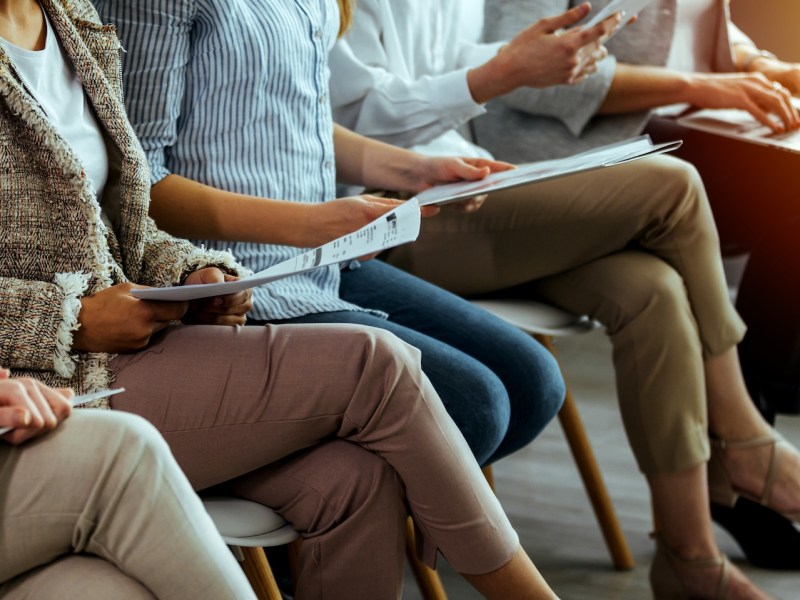 Eine große Gruppe von Bewerbenden wartet auf ein Vorstellungsgespräch.