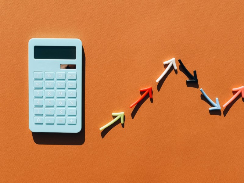 Blauer Taschenrechner und ein Diagramm aus farbigen Pfeilen.