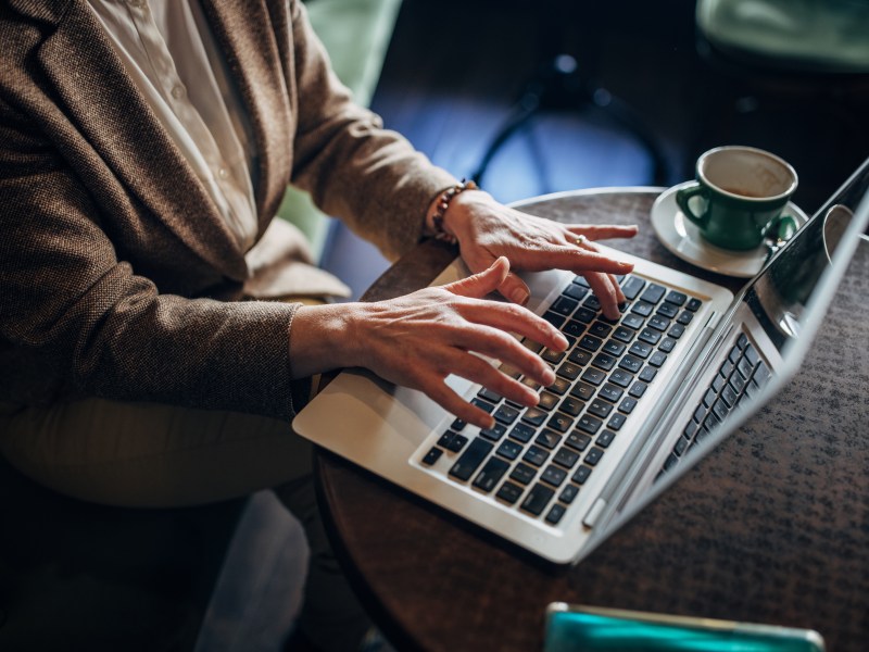 Eine Frau arbeitet in einem Café an ihrem Laptop.